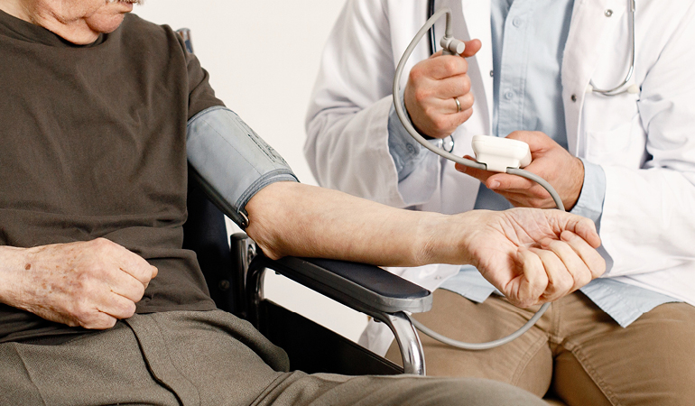 A senior patient having their blood pressure checked by a nurse in a Senior care home for high blood pressure elderly near Delhi.